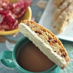 Pomegranate White Chocolate Biscotti sitting on top of a mug of coffee