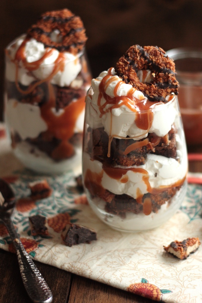 2 Samoa brownie parfaits in stemless wine glasses with cookie pieces scattered around them