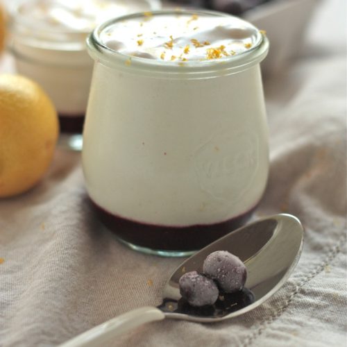 Lemon Blueberry Mousse in glass jar with spoon in foreground with two blueberries on it