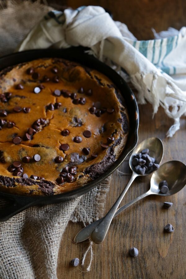 Cheesecake Skillet Brownie on a wood table with two spoons on the side