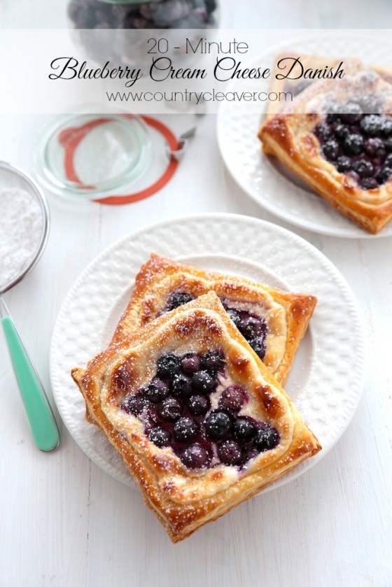 Blueberry Danish on white background with powdered sugar and white plates