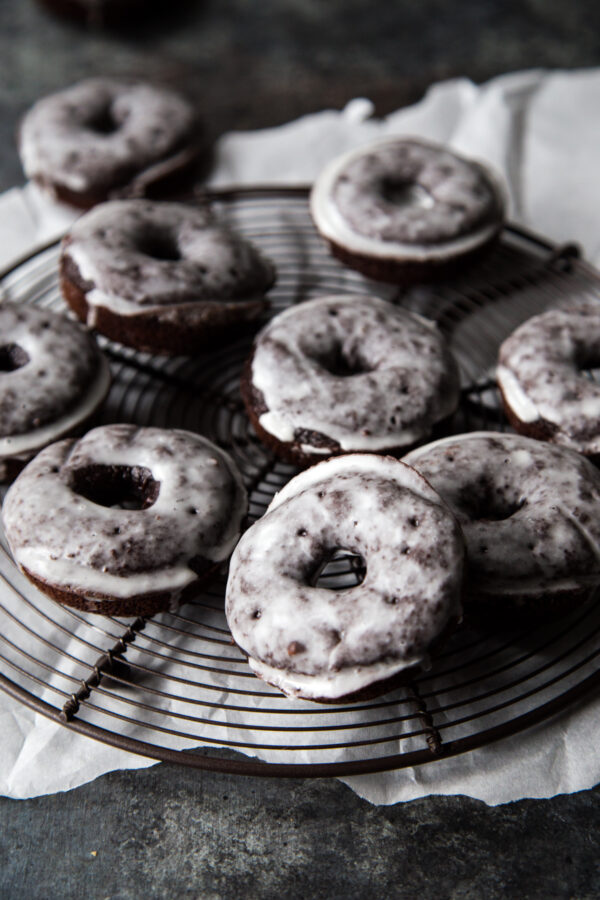 Stack of chocolate glazed cake doughnuts on a wire rack set on top of parchment paper