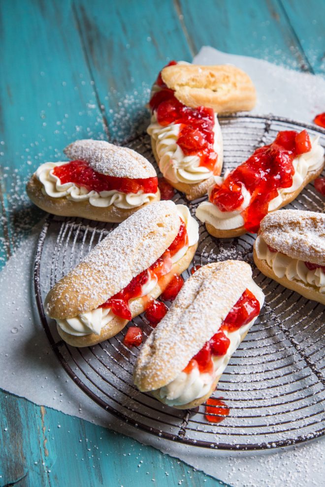 Strawberry Cheesecake Eclairs on a blue background and cooling rack
