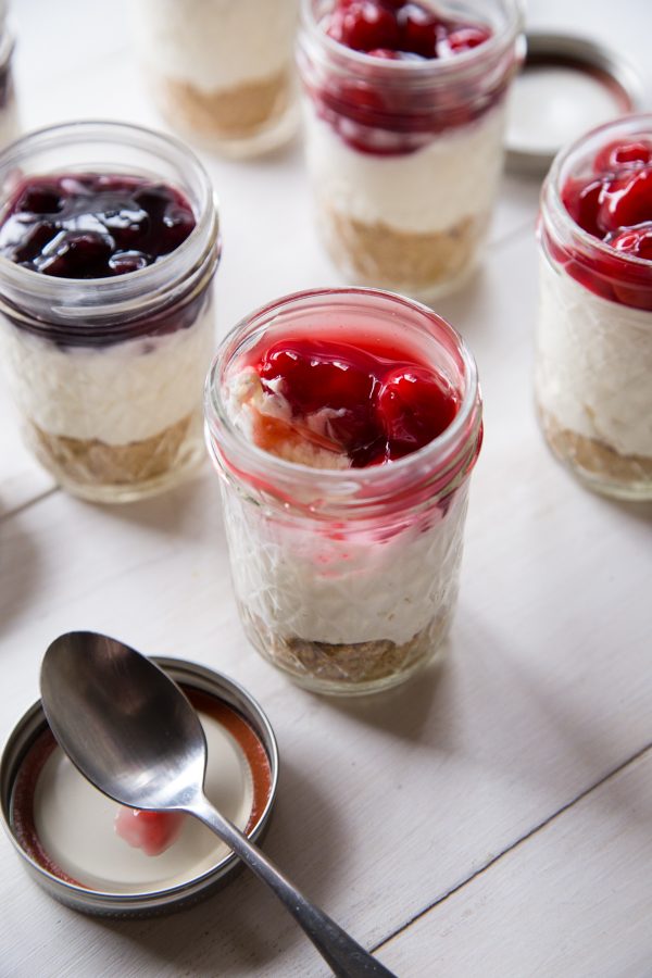 No Bake Cheesecakes In A Jar with cherries and blueberries and spoon 
