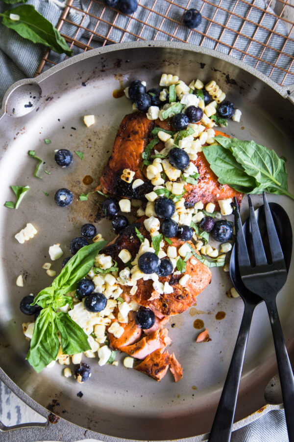 Wild Salmon with Blueberry Corn Salsa in a cast iron pan with black utensils