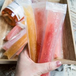Tropical Fruit and Guava Frose Pops with rose bottle on a serving tray holding 3 popsicles