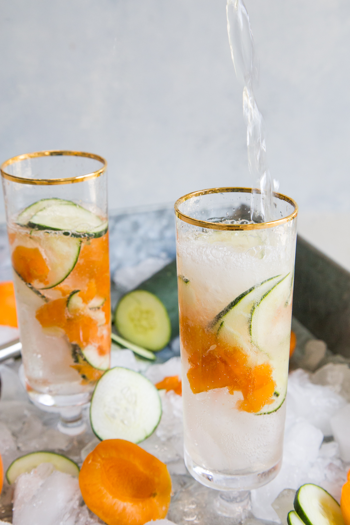 Apricot cucumber gin fizz in two glasses being poured
