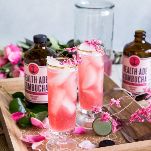 Pomegranate Kombucha St Germain Spritzer Cocktail with roses and two bottles