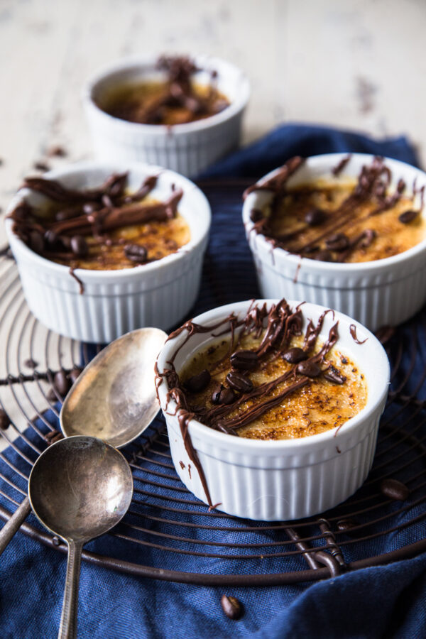 Coffee Creme Brulee with Chocolate Drizzle on cooling rack with blue napkin and spoons