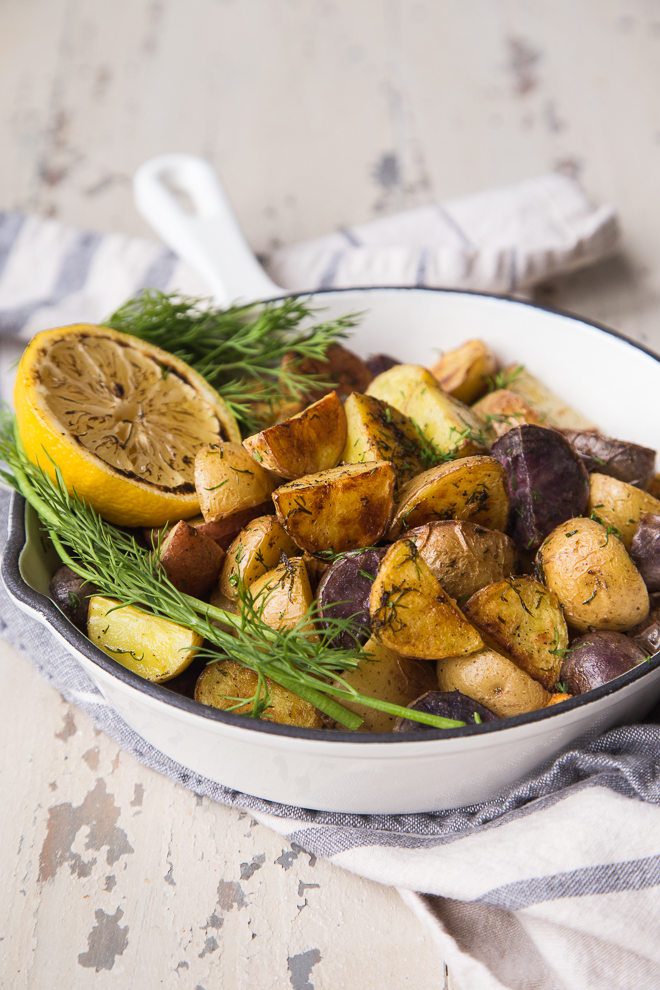 Roasted potatoes with dill and lemon in white enamel skillet