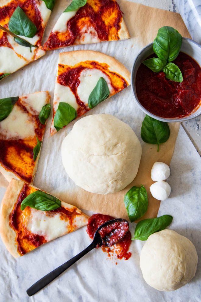 No fuss five minutes pizza dough, made in a food processor! Dough ball surrounded by cut pizza margarita 
