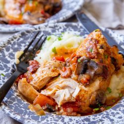 Instant Pot Rustic Braised Chicken set on mashed potatoes in a shallow gray and white bowl