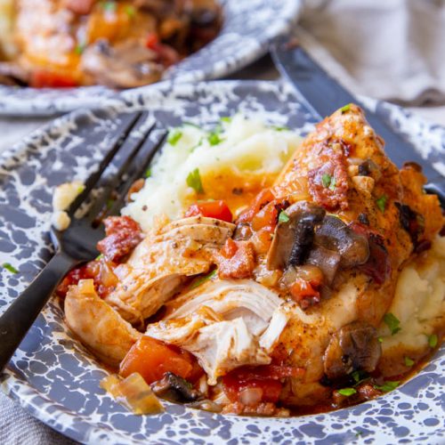 Instant Pot Rustic Braised Chicken set on mashed potatoes in a shallow gray and white bowl
