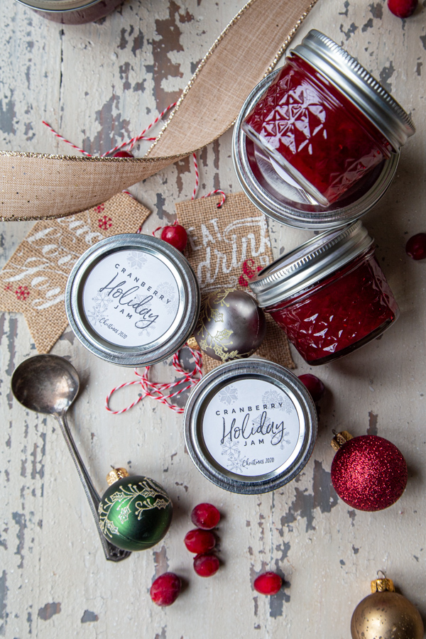 cranberry holiday jam with jars surrounding it overhead with christmas ornaments