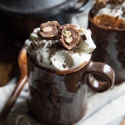 nutella hot cocoa in dark purple cups with chocolate surrounding it