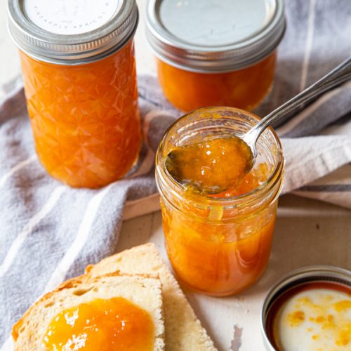 Pineapple Apricot Jam on bread, with jars of jam in background