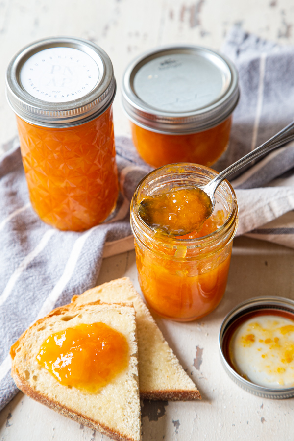 Pineapple Apricot Jam on bread, with jars of jam in background