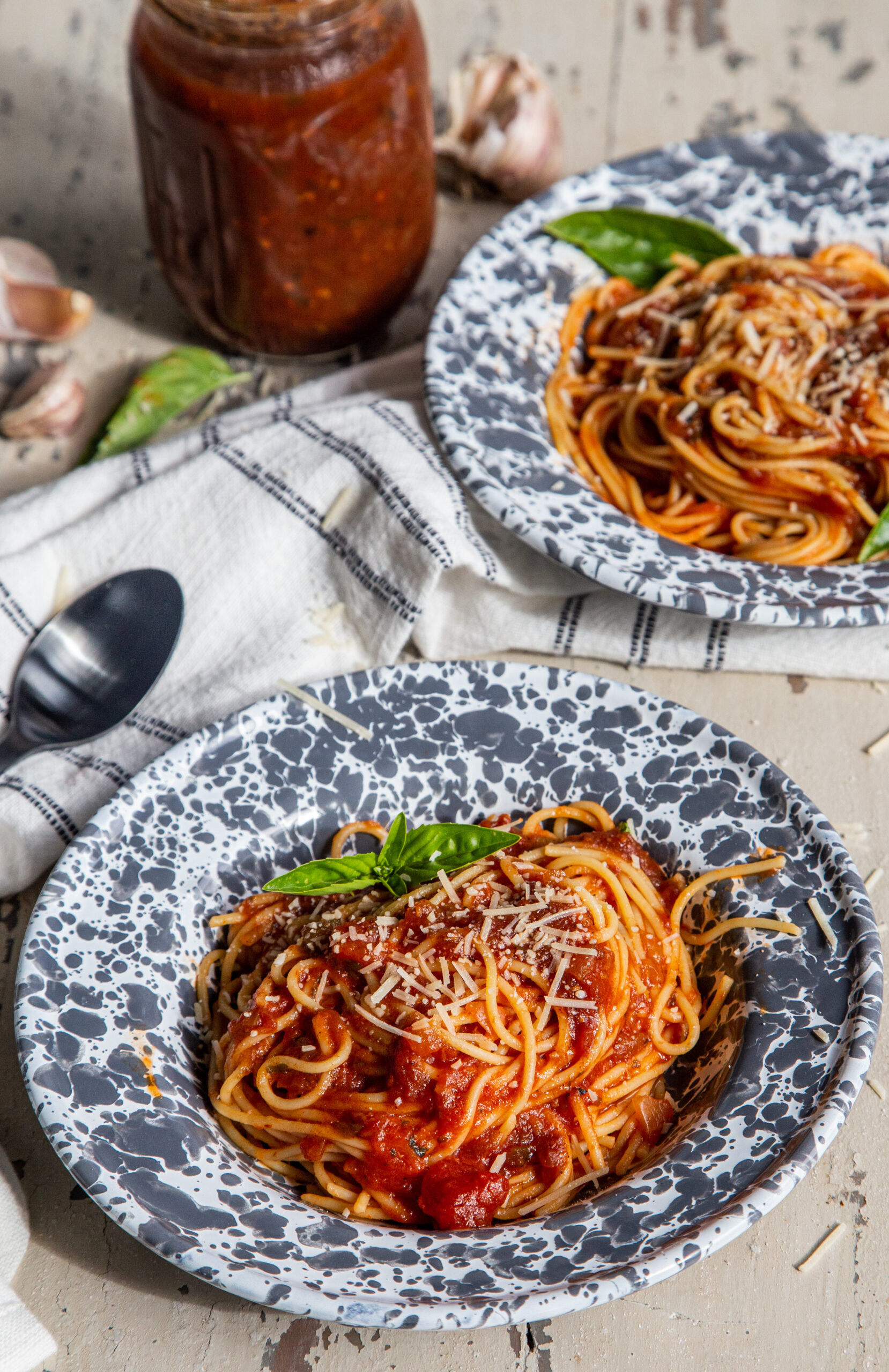 Two bowls of spaghetti with Grilled Pepper and Onion Pasta Sauce with jar of sauce in background