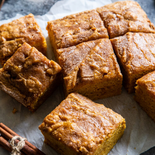 Squares of pumpkin snack cake on parchment paper