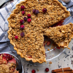 Overhead view of Cranberry Dutch Apple Pie in glass pie plate and slice on small plate with fork