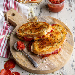 Pepperoni Pizza Grilled Cheese on a cutting board with pizza sauce in a jar